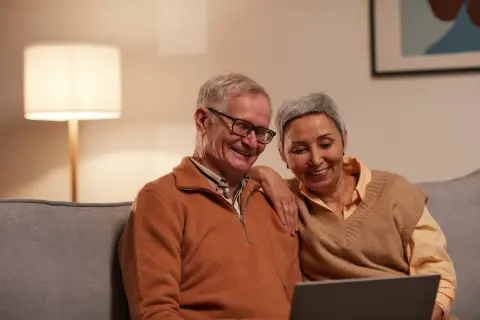 an image of two older adults reading something on digital screen