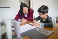 an boy doing homework with his mom