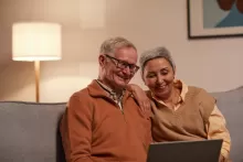 an image of two older adults reading something on digital screen